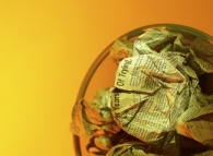 Yellow photo of newspapers in a trash can